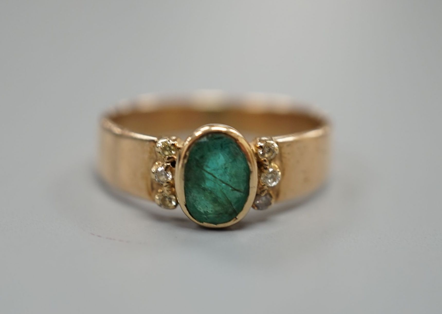 A yellow metal, oval cut emerald and six stone diamond chip set ring, size O, gross weight 3 grams.